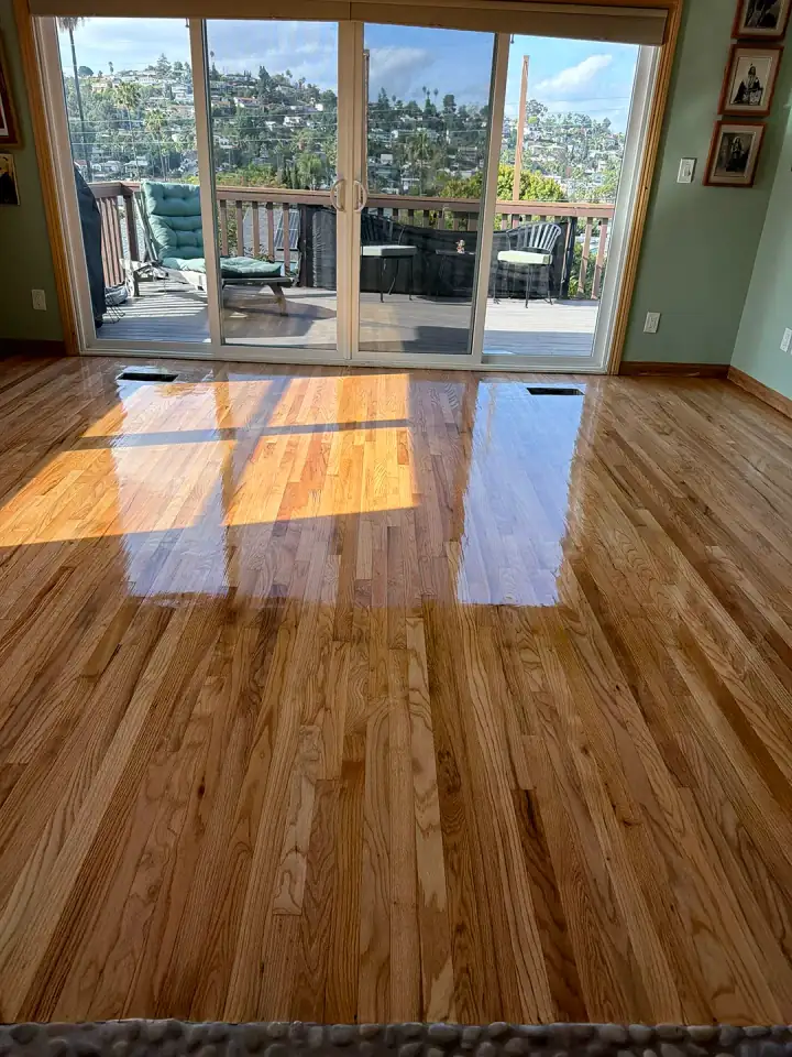 After: refinished red oak living room floor with a glossy, even finish