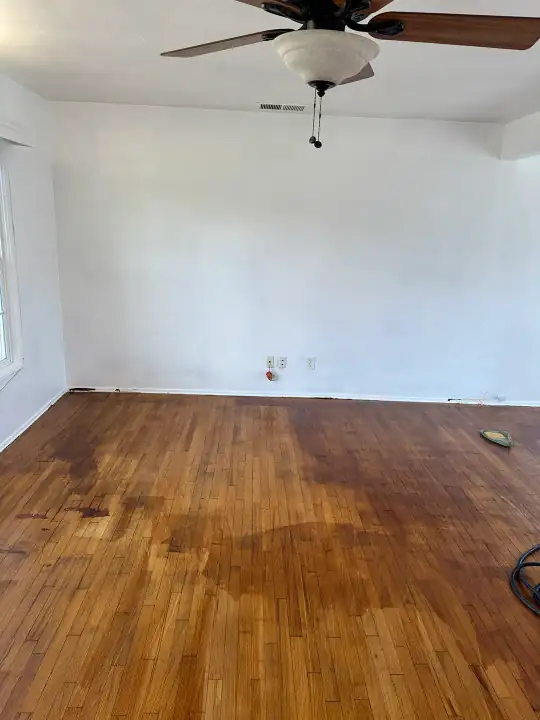 Before: living room hardwood with dark stains and uneven color