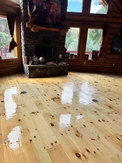 High-gloss pine floor beside a stone fireplace